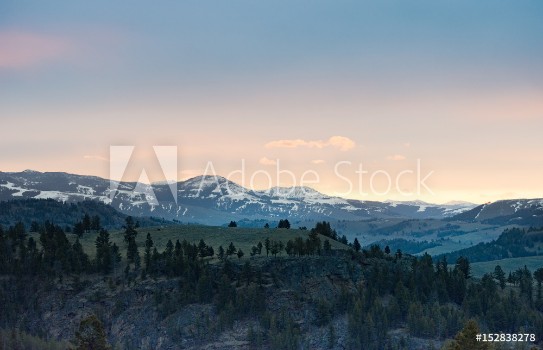 Picture of Panoramic view of sunrise over snow capped rugged mountains with smaller rocky hills in the foreground Photographed in natural light in Yellowstone National Park